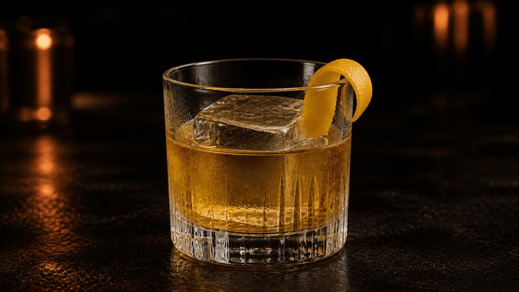 Gold Rush i ett lågt glas över en stor iskub med klar gyllene drink och en bred citrontwist.