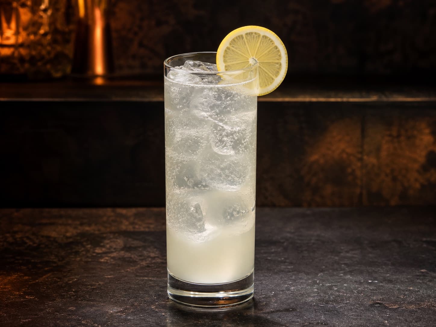 John Collins i ett highballglas med is, citron och klar bubblig drink.