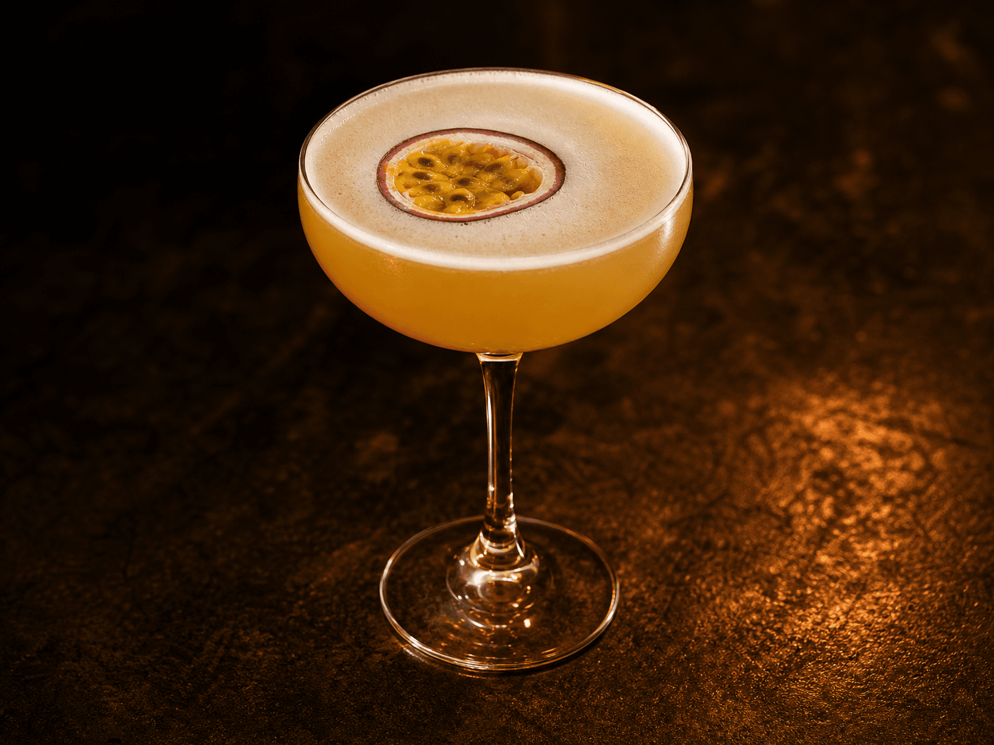 Vanilla Passion i ett coupeglas med gyllene passionsfruktsdrink och halverad passionsfrukt.