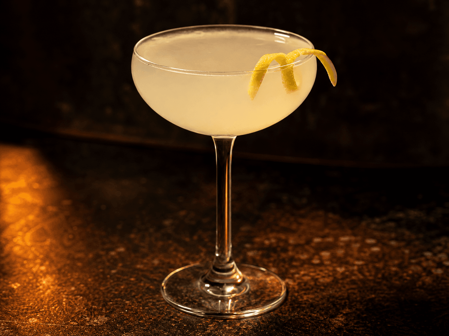 White Lady i ett kylt coupeglas med klar ljus cocktail och citronzest.