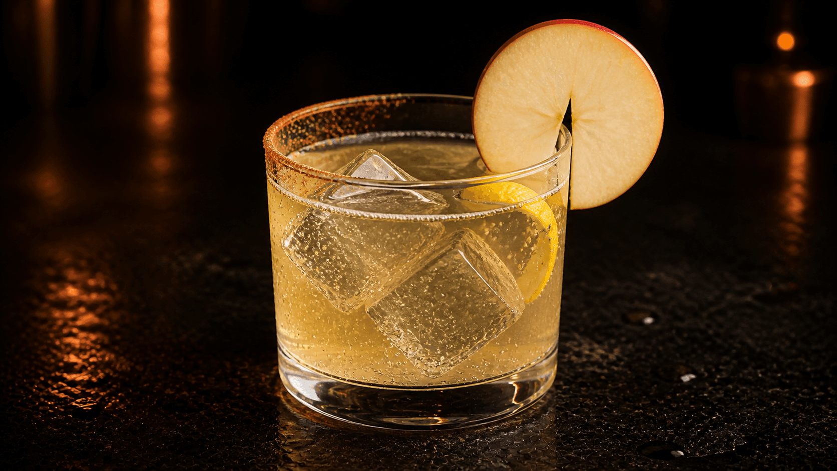 Äpple & Honung 0% i ett lågt glas med blekt gyllene, bubblig drink, is, en tunn äppelskiva över kanten, citrontwist och tunn kanelsockerkant.
