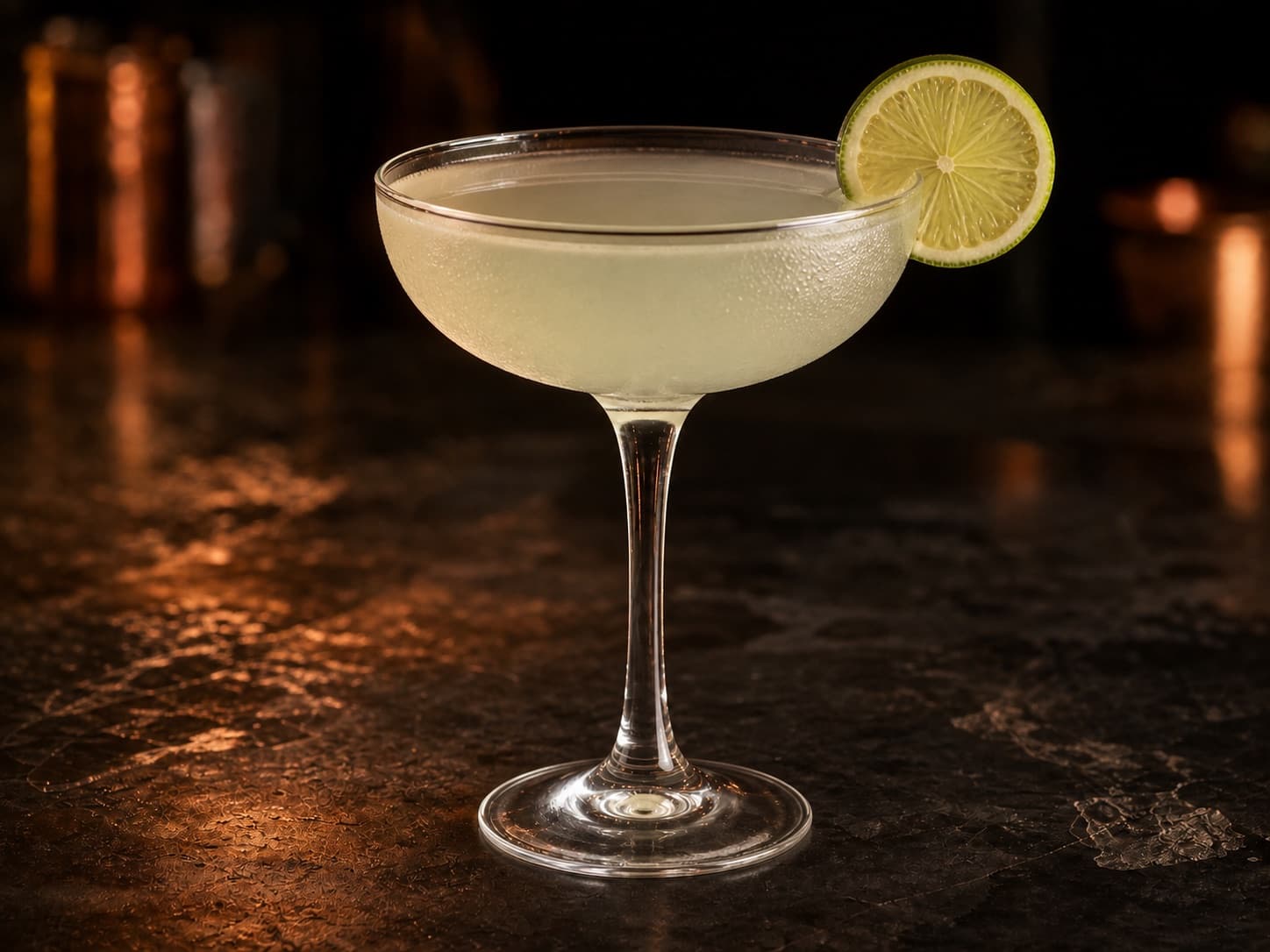 Kamikaze i ett kylt coupeglas med klar, ljust grönaktig cocktail.